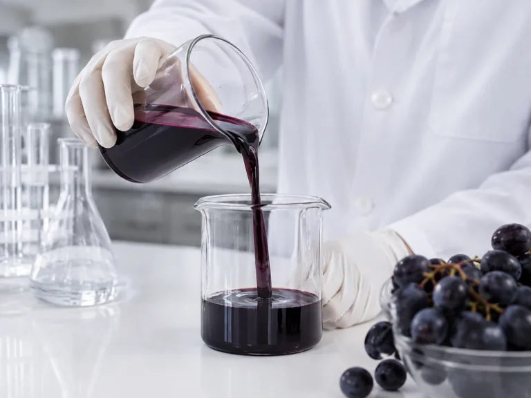 Black grape juice concentrate being poured into a laboratory beaker for quality analysis